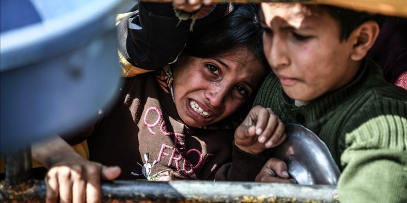 Crianças aguardam atrás de grades por longas horas, na esperança de obterem um pouco de comida, item raro desde as ações das forças israelenses para impedir a chegada de ajuda humanitária em Gaza. Foto de Abed Zagout - Agência Anadolu